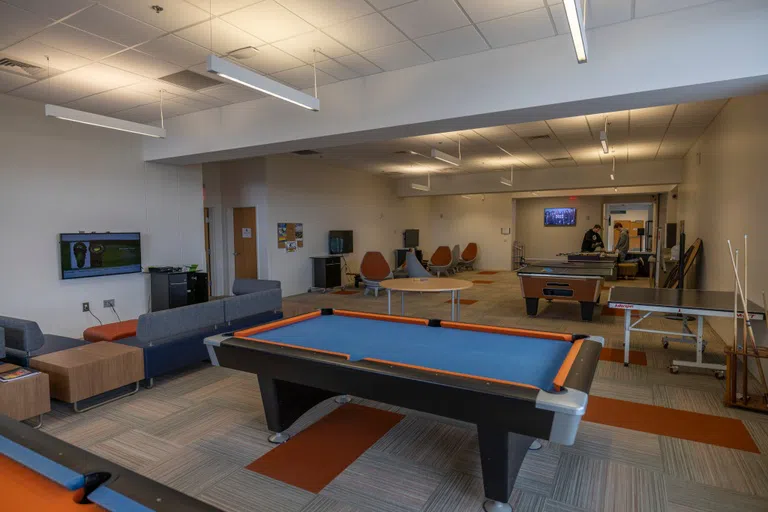 Pool table in the foreground, with additional gaming tables in the background. 