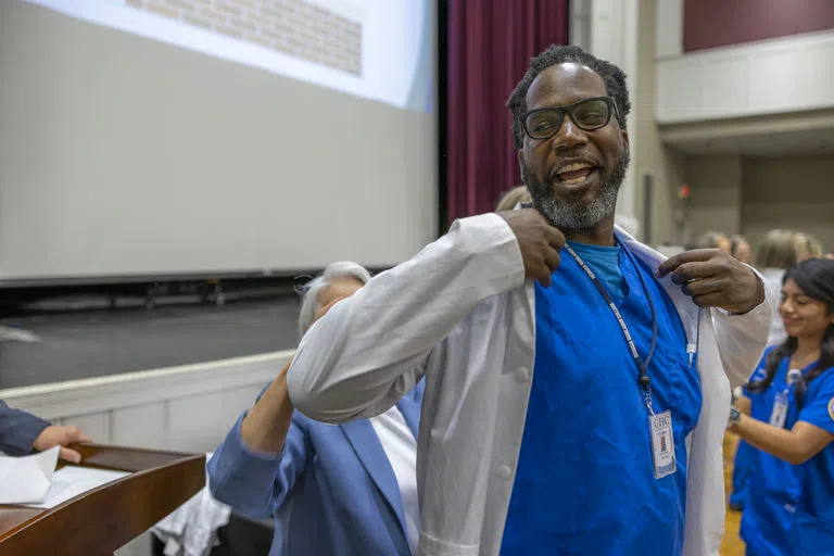 Nursing student receives white coat upon completion of courses. 