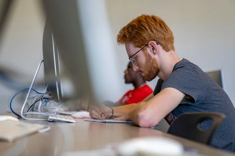 Student focused on studying in front of a desktop computer