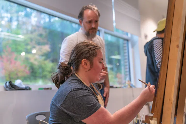 Student paints in front of instructor in the Arts Lab