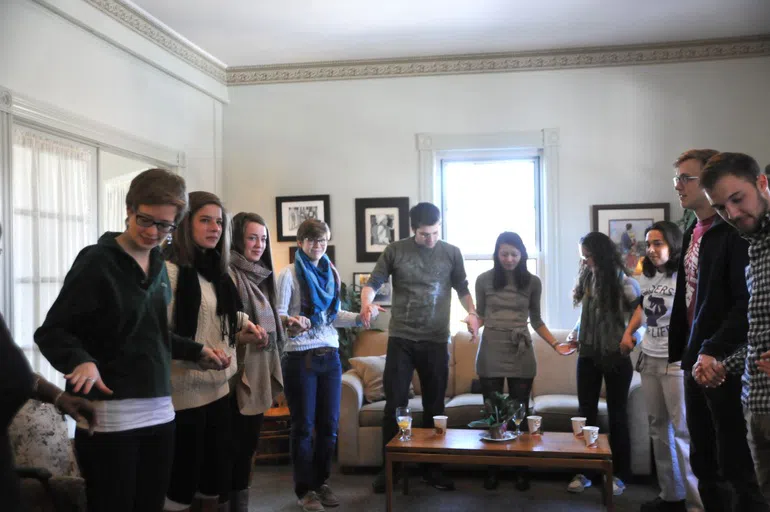 Students and chaplains holding hands in prayer.