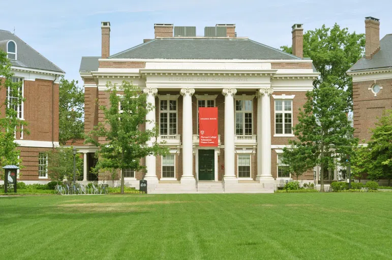 Columns building with red banner at the edge of grassy lawn