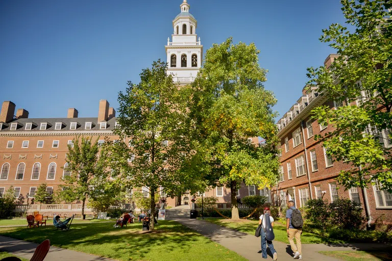 Students walk in courtyard, surrounded by trees and dormitory complex