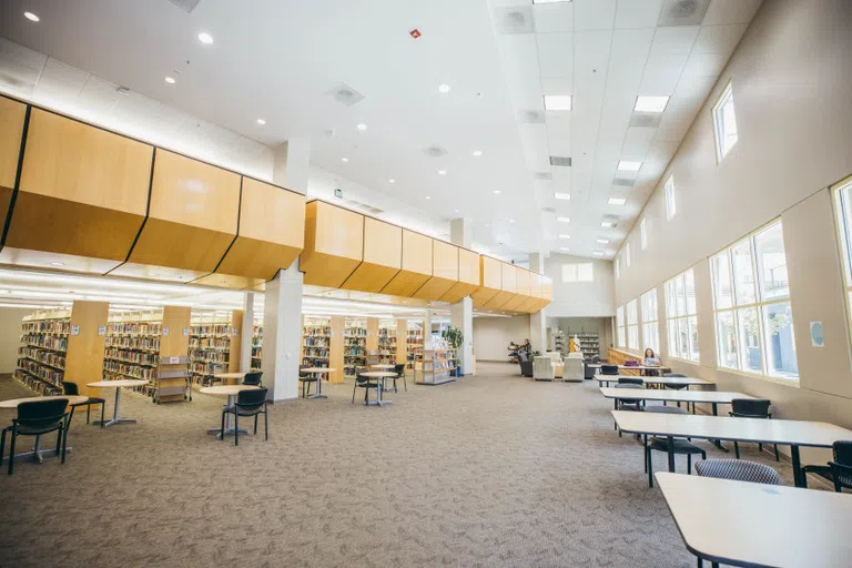 Nystrom Library study spaces with rows of books and private or shared tables