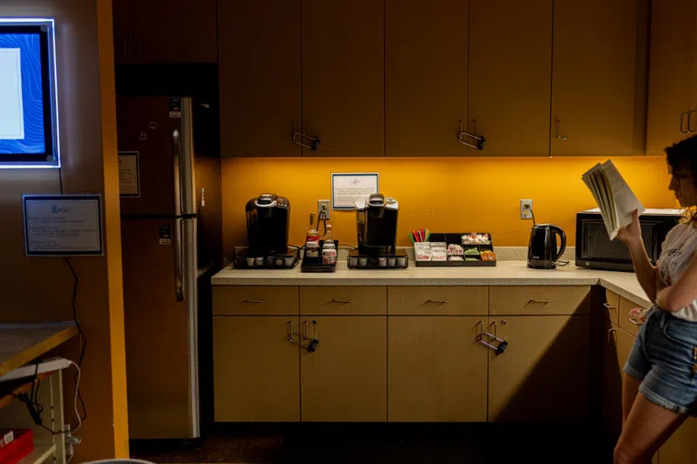 Full coffee bar in Commuter Kitchen featuring a fridge. student reading a book.