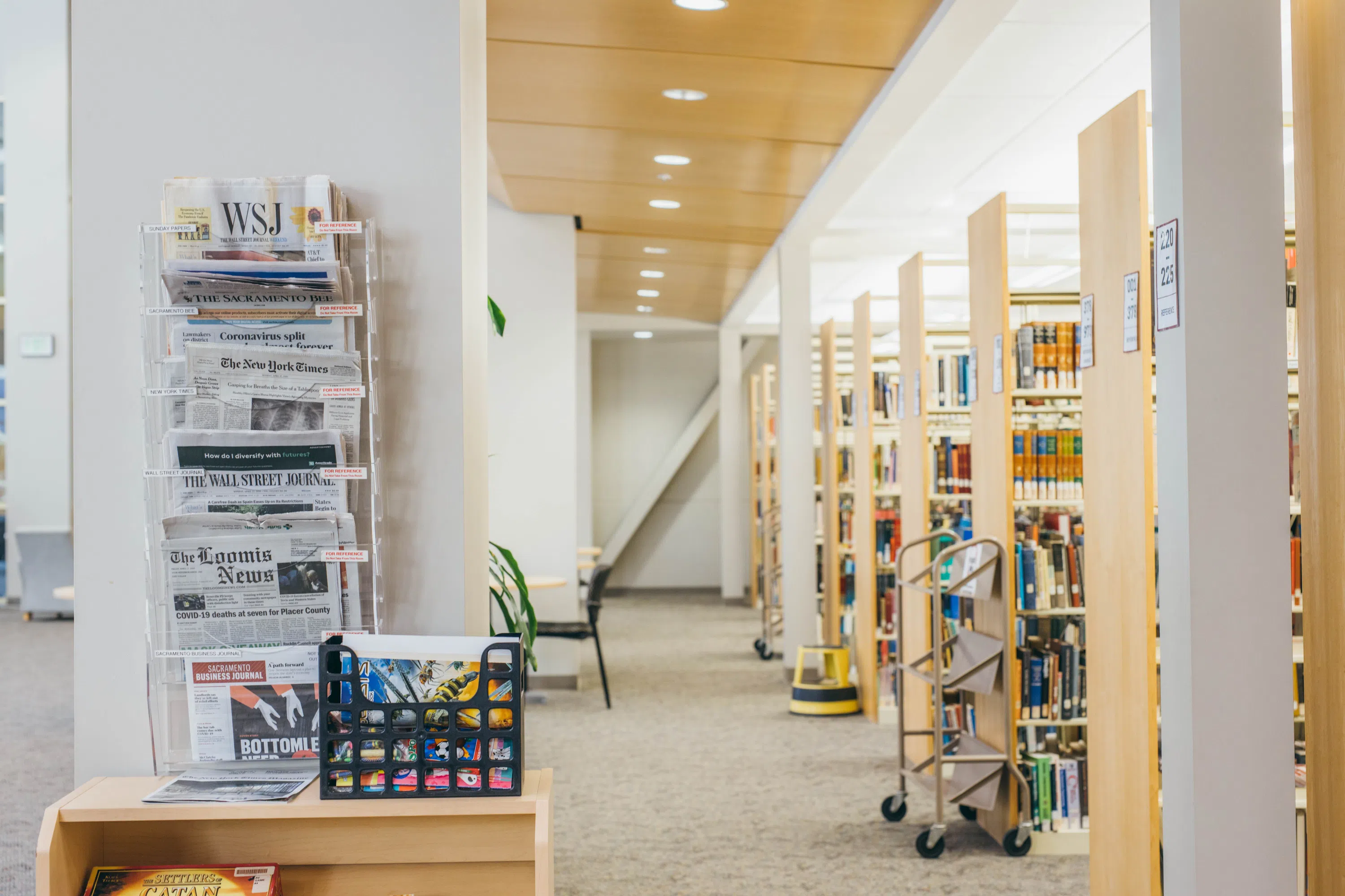 Hallway featuring news papers from major outlets and rows of books