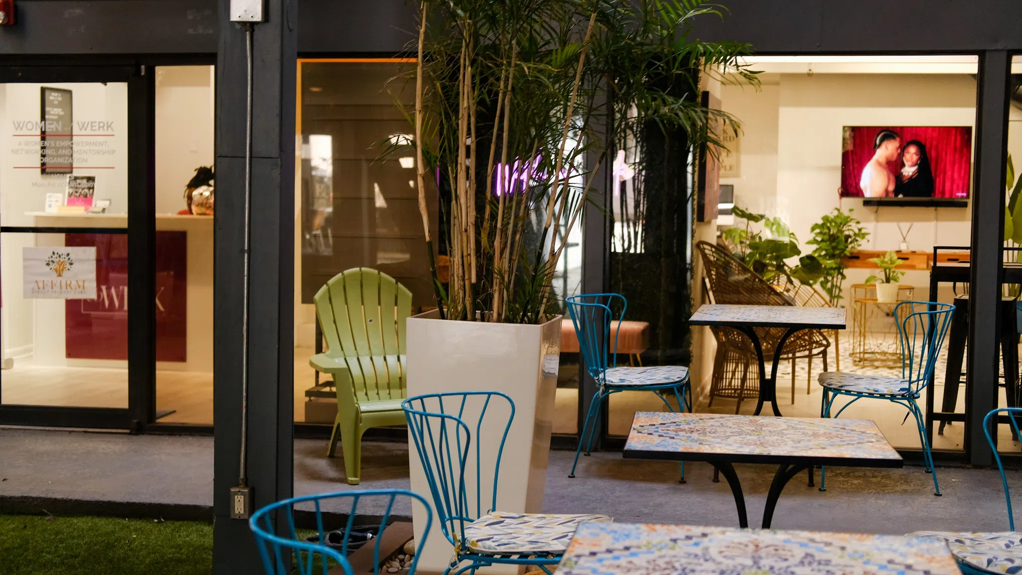 Tables and chairs arranged in an indoor/outdoor hybrid garden.