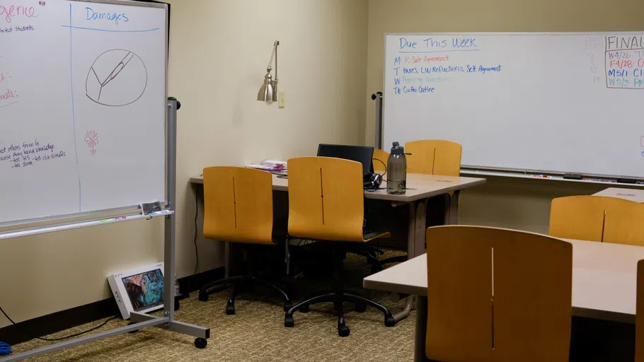 A room with group tables and white boards for collaborative study.