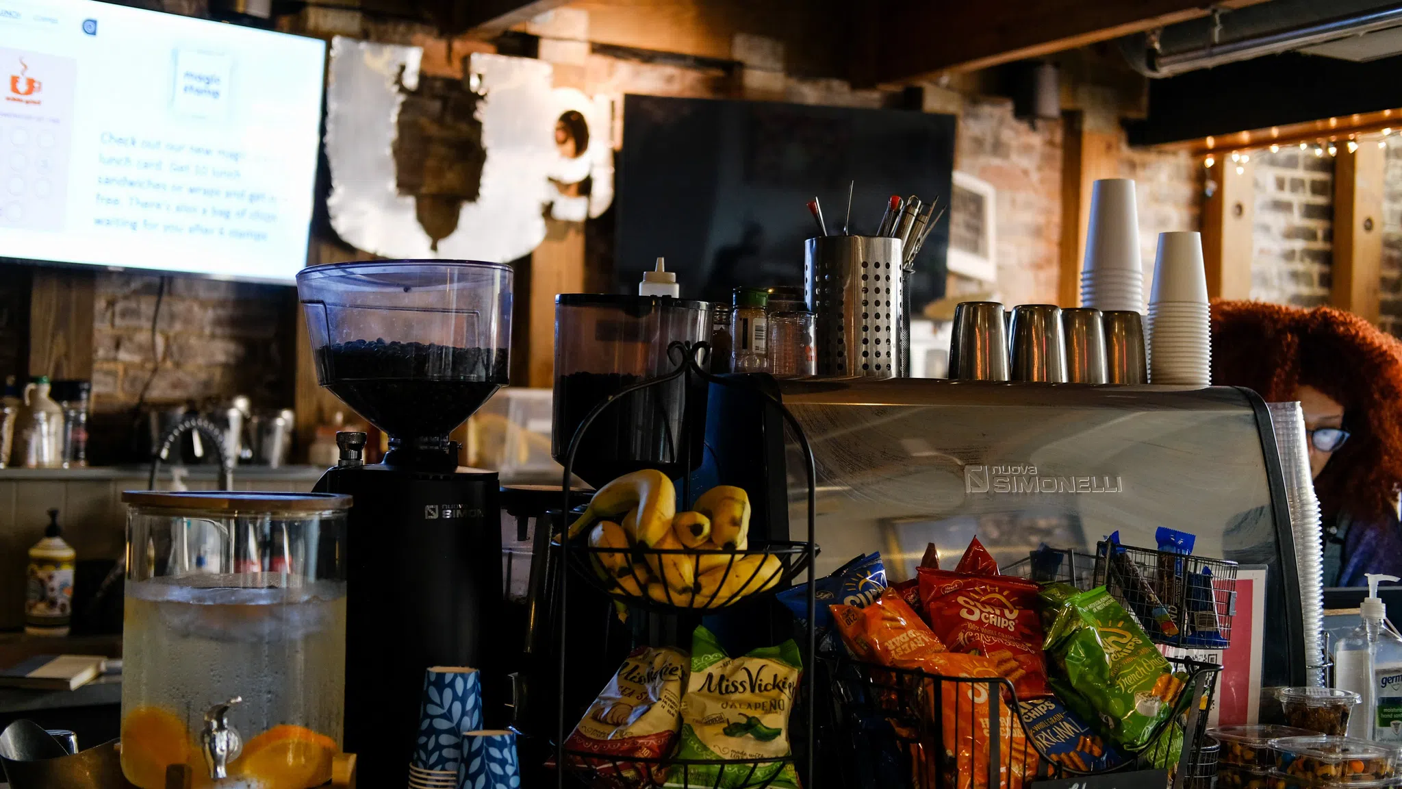 An ordering counter with baked goods, chips, and fruit bowls arranged for customers to see..