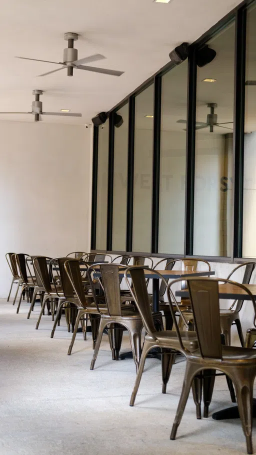 A covered patio area with multiple seating options lined along the windows, with metal chairs.