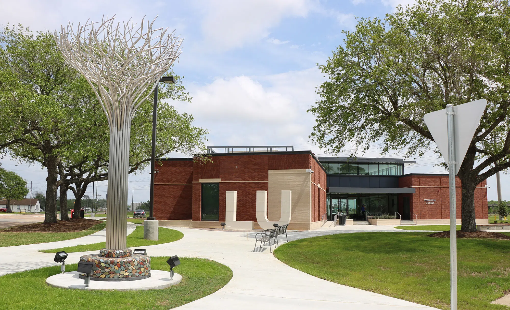 image of green grass, metal tree statue, LU statue and red building labeled as Ken and Nancy Evan Welcome Center