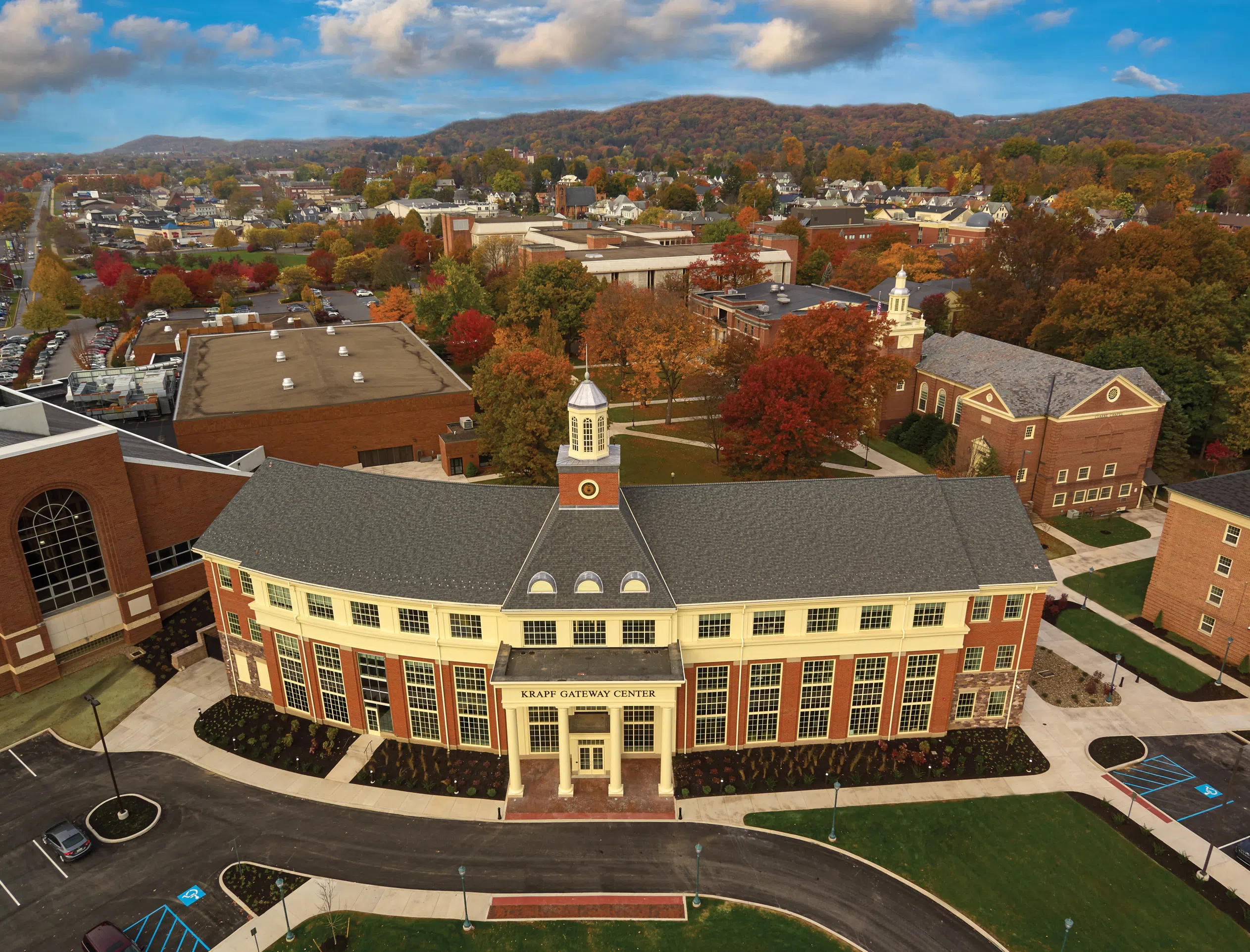 An autumn aerial view of Lycoming's campus, with the Krapf Gateway Center at the forefront and colorful mountains in the distance.