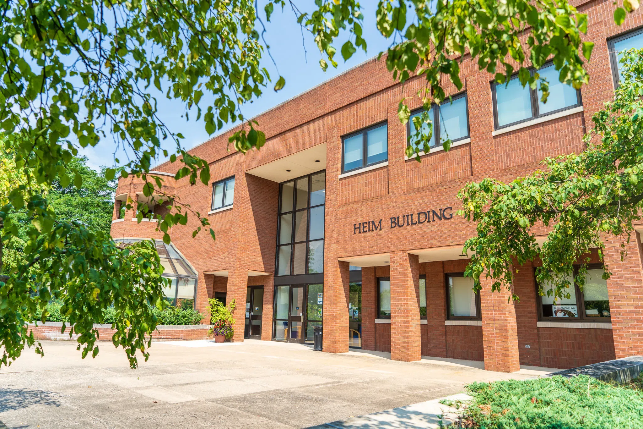 A view of the Heim Science Building through the trees in July.