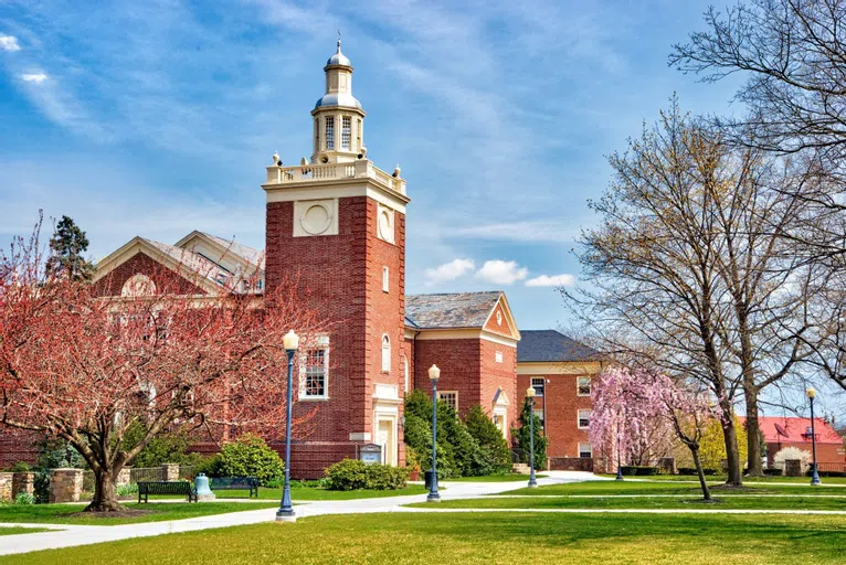 A view of Clarke Chapel and its bell tower in spring surrounded by blossoming trees.