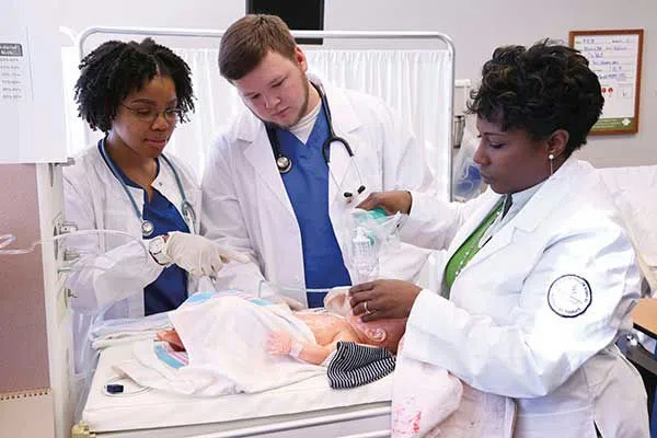 A group of nursing students work in the simulation lab.