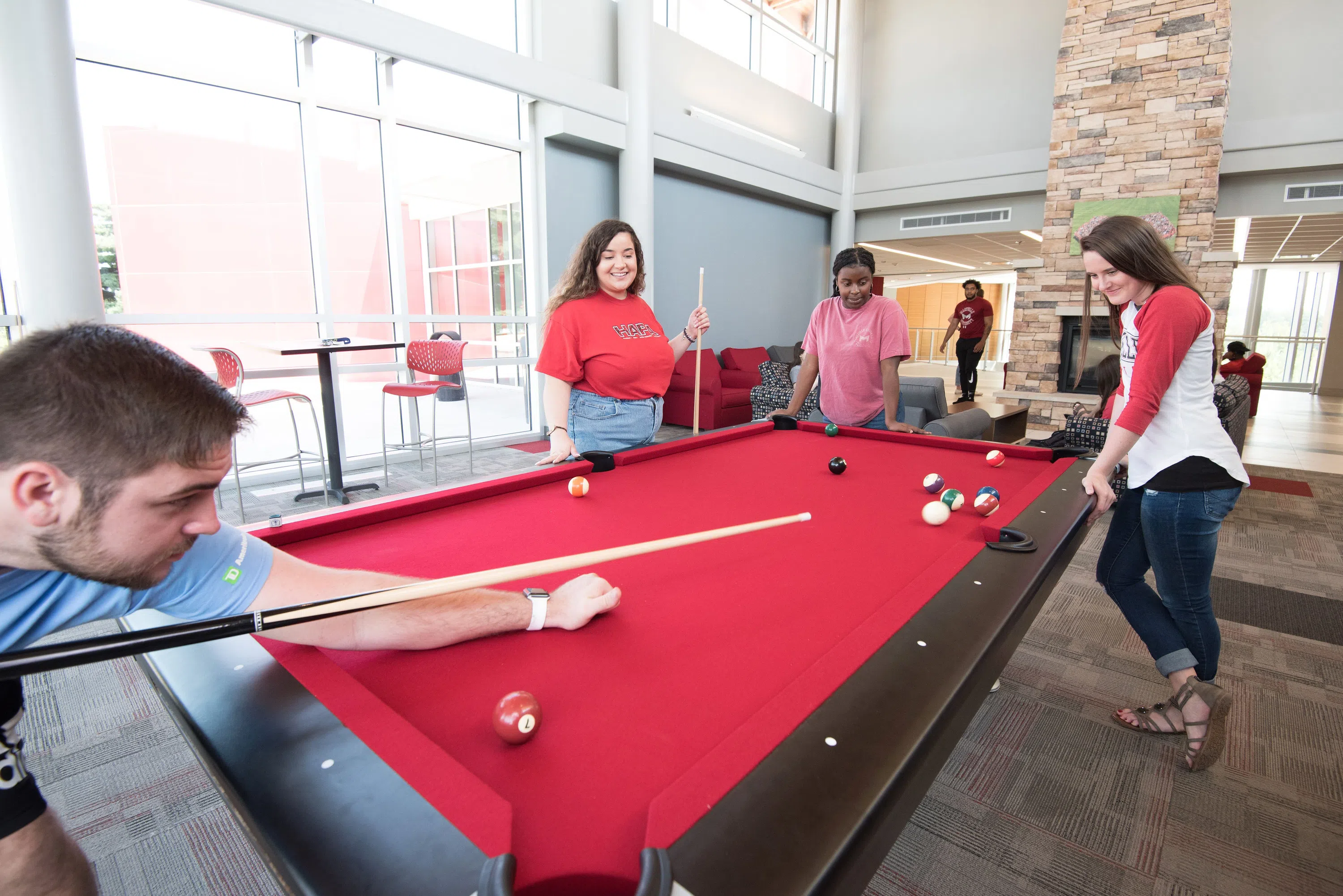 Students spend time in the "lodge," the main lobby in Saints Hall, playing pool, sitting by the fireplace, and chatting on the couches.