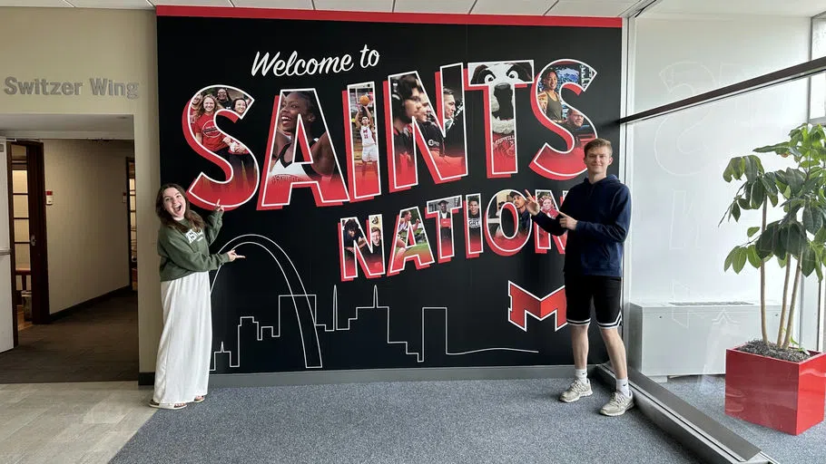 Two students point to the welcome wall