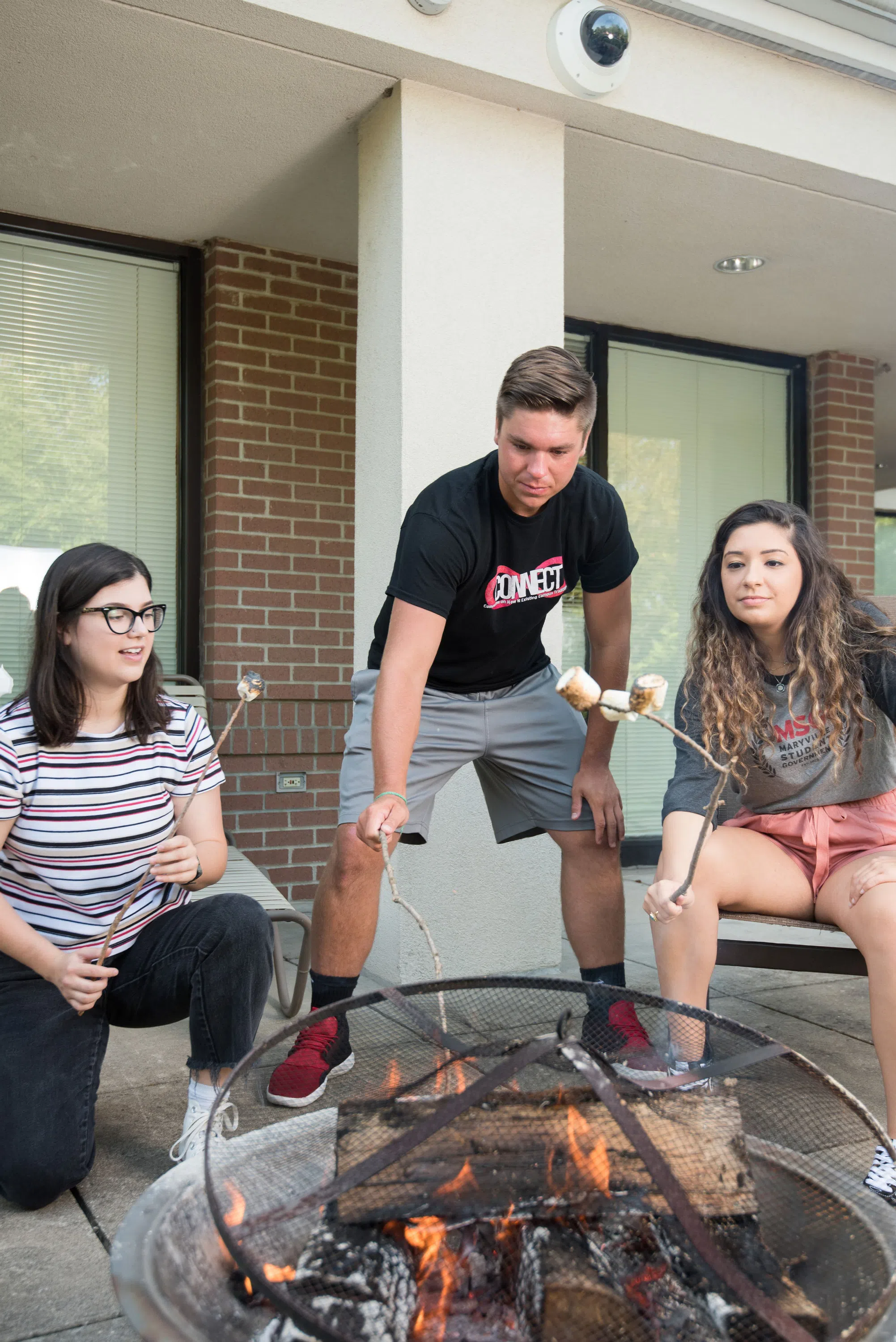 Students roast marshmallows over a fire in the courtyard behind Potter Hall. 