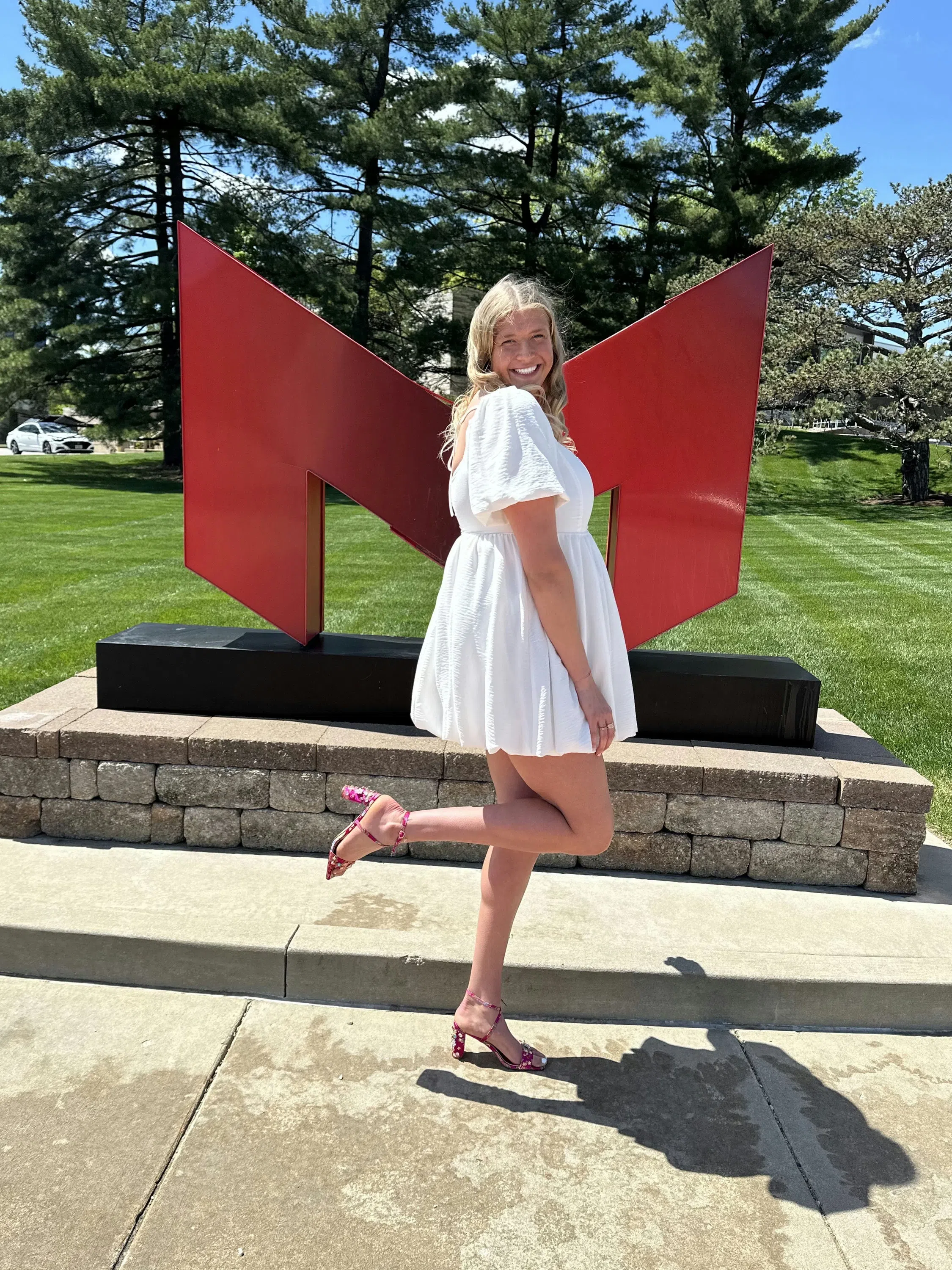 A Maryville Saint stands in front of the Big Red "M" in a white dress.