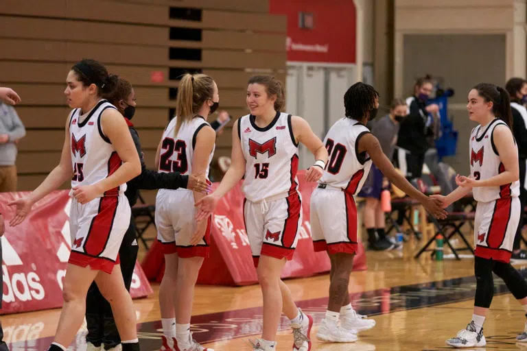 Members of the women's basketball team come together in Maloney Arena in the Simon Athletic Center.