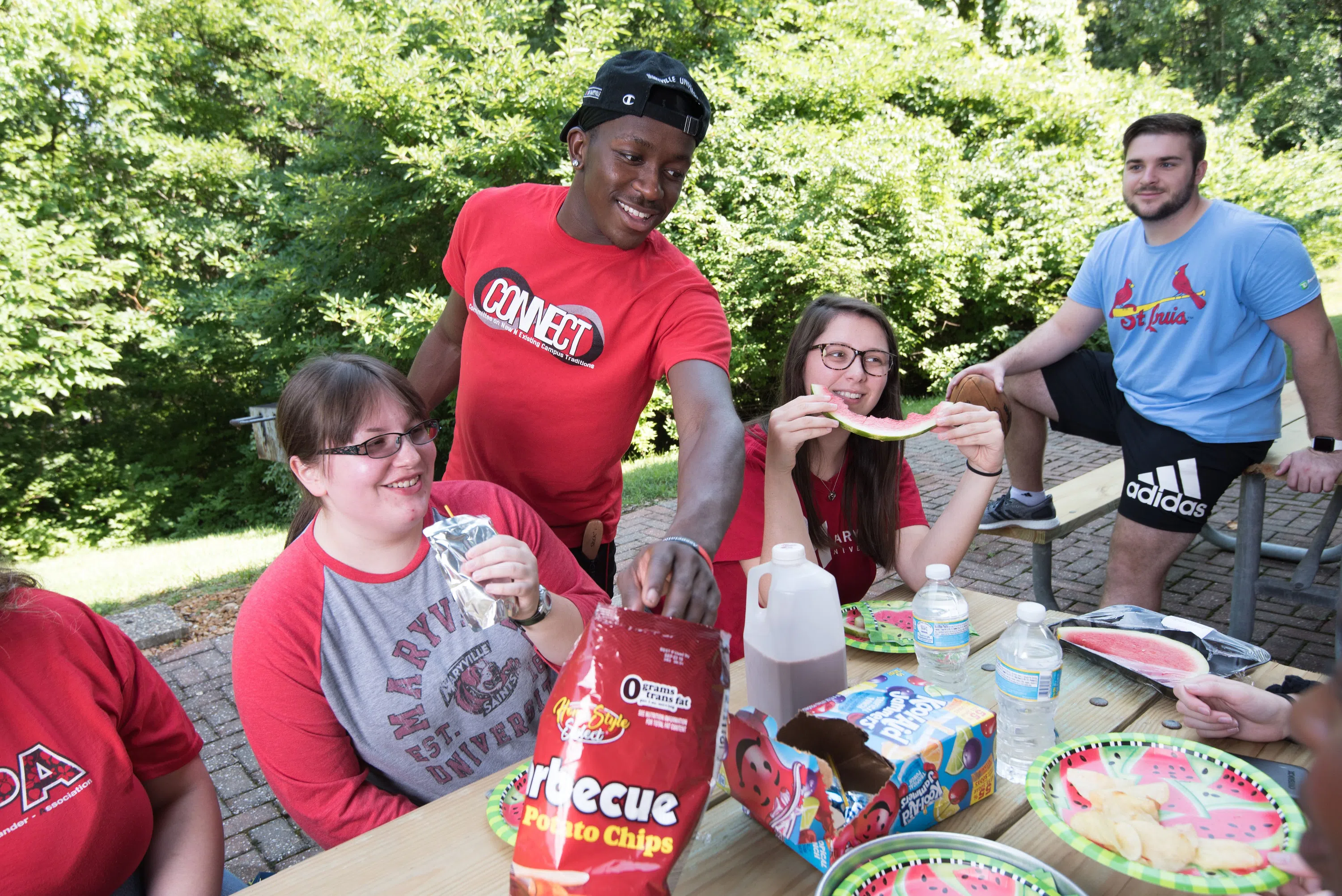 Students eat around a picnic table behind the apartment building.