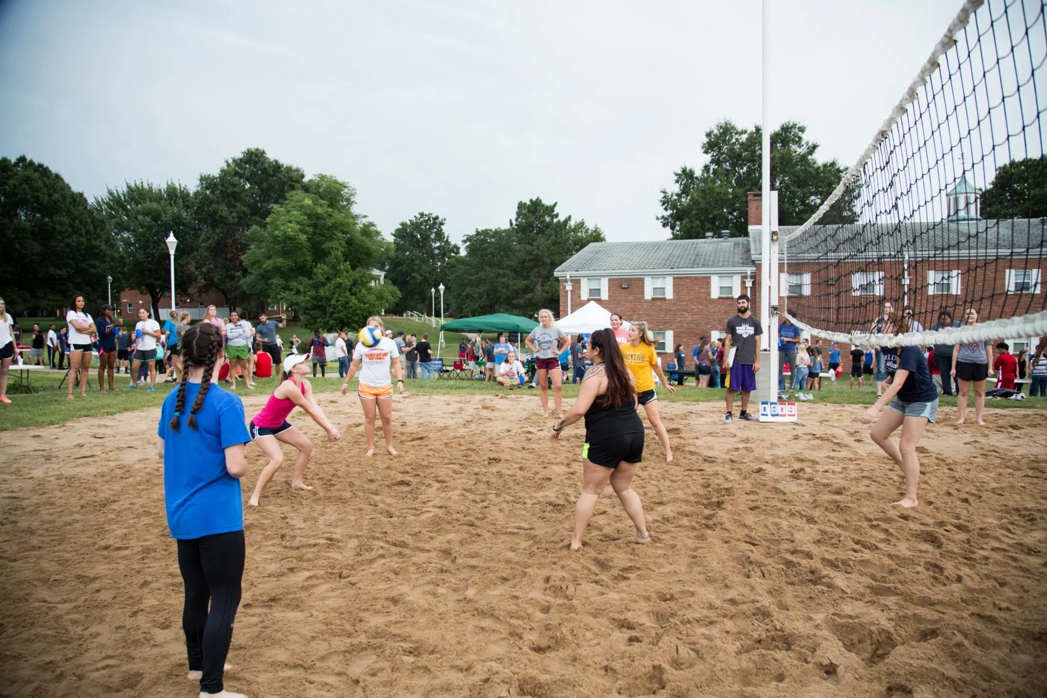 Students play volleyball on the sand volleyball courts