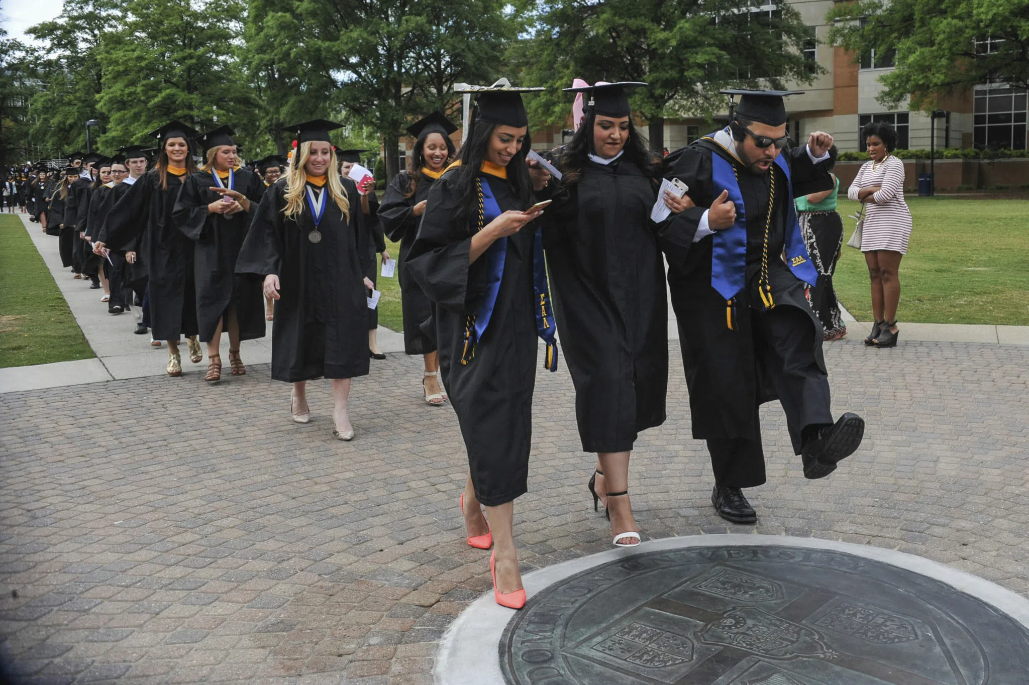 Students walk on the seal during commencement