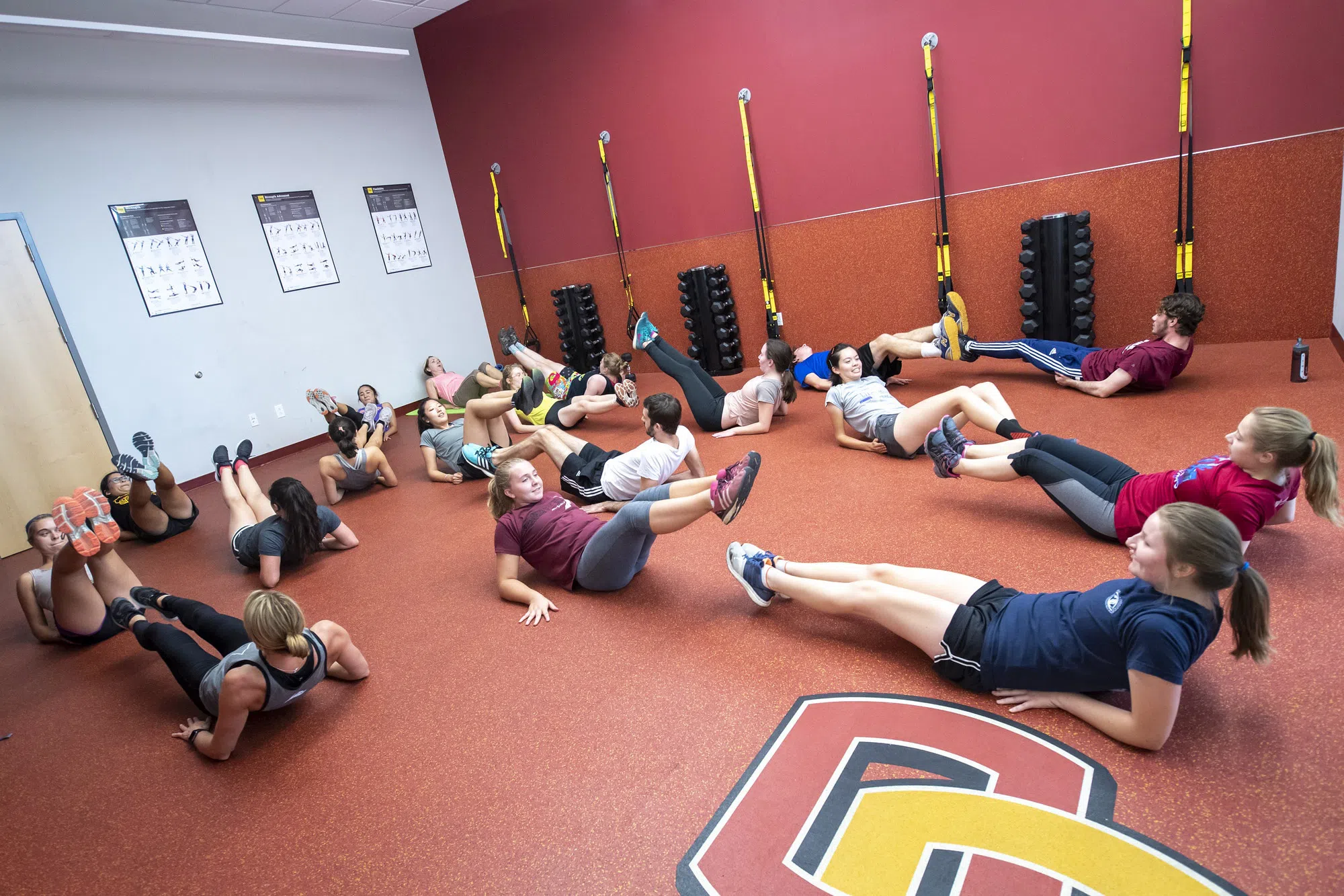 People in athletic wear do ab exercises in a fitness room.