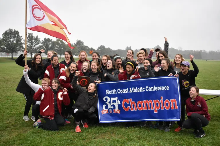 A group of students celebrate their win as they hold up a poster that says 35th Champion of the North Coast Athletic Conference.