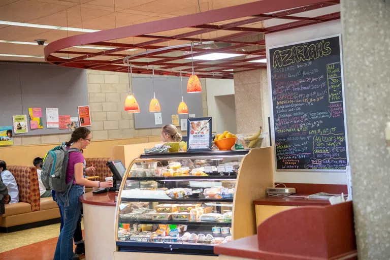 A student orders a warm beverage and a snack at Azariah's Cafe.