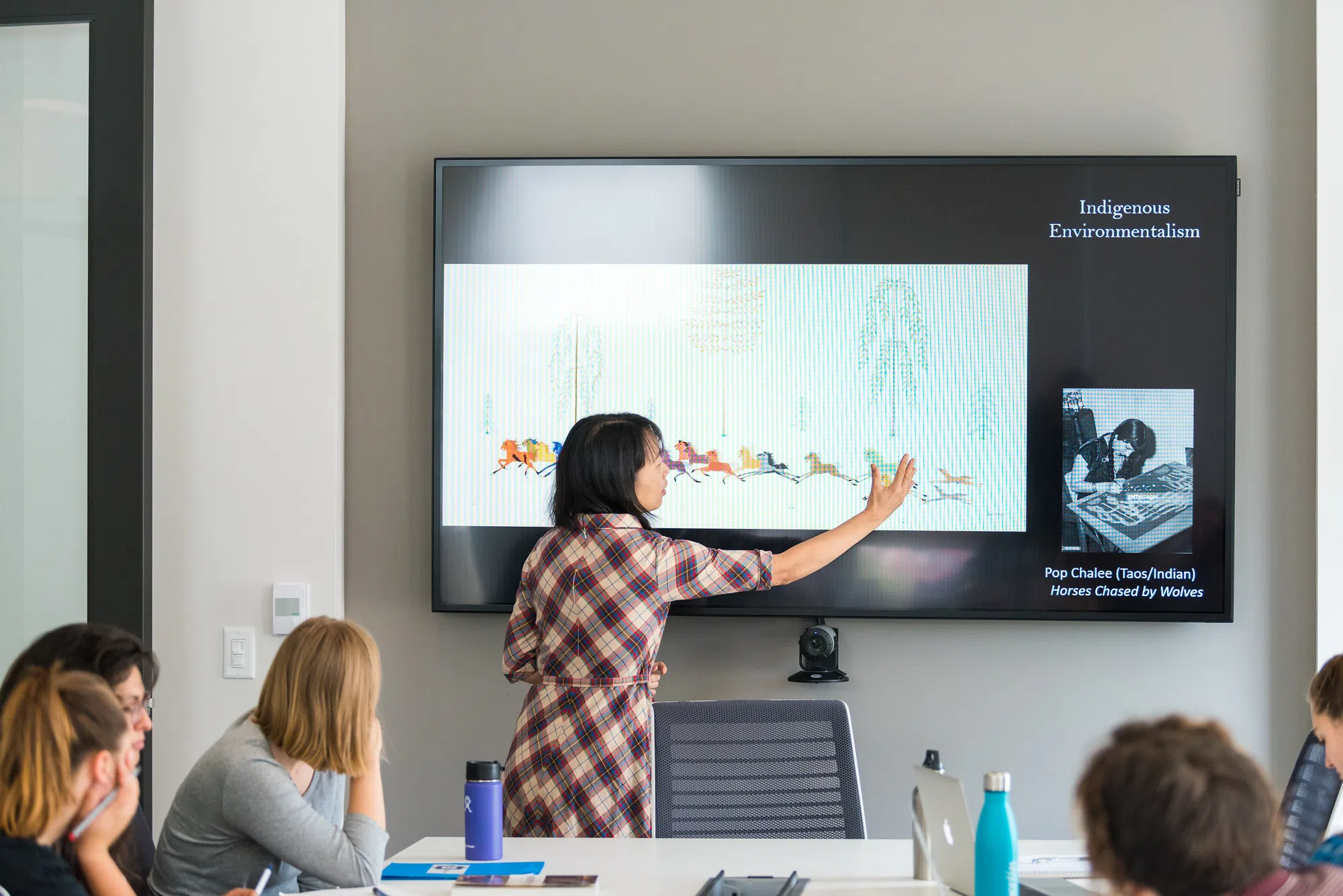 A presenter stands in front of a powerpoint that says Indigenous Environmentalism.