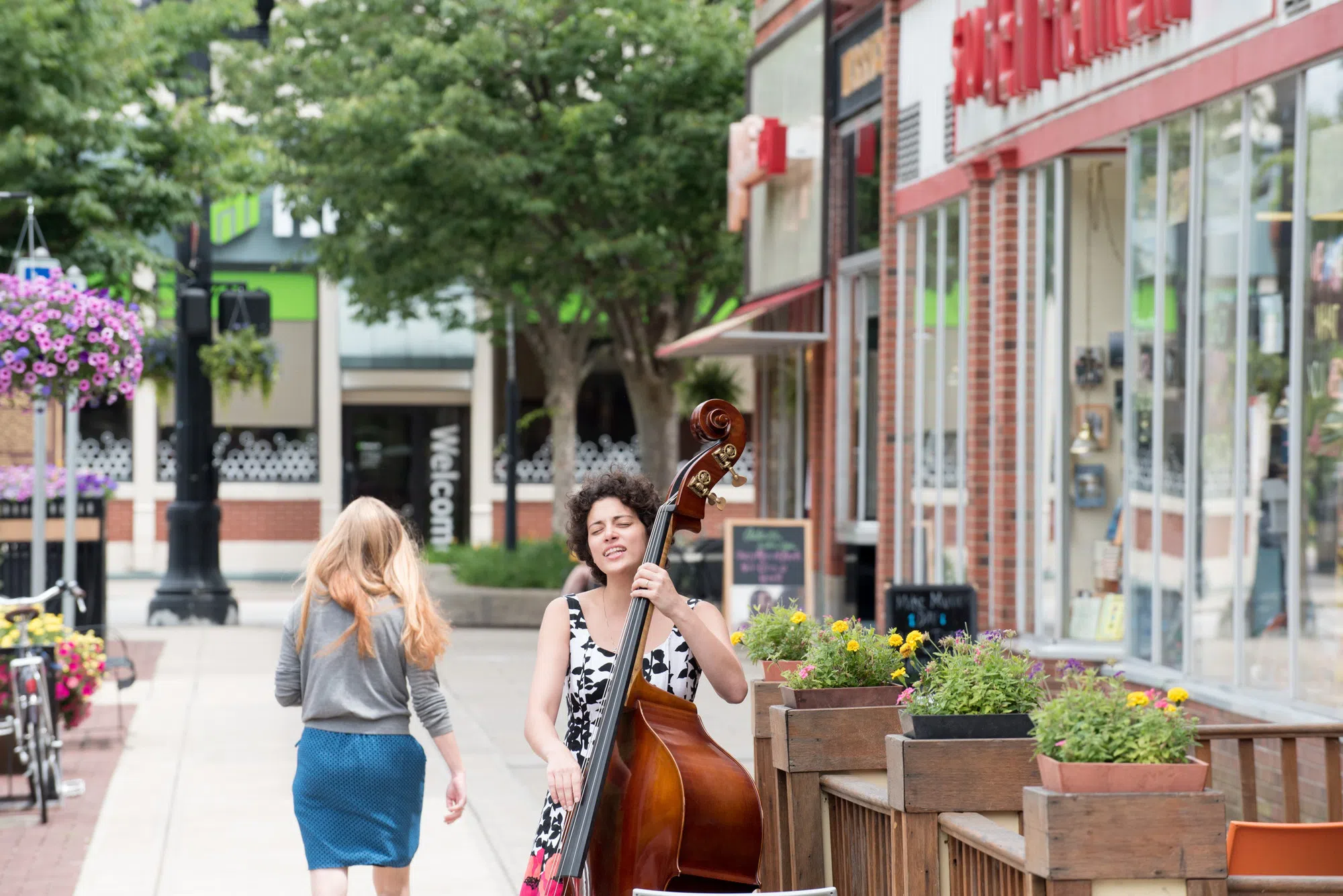 A student plays her upright bass in front of a business in downtown Oberlin.