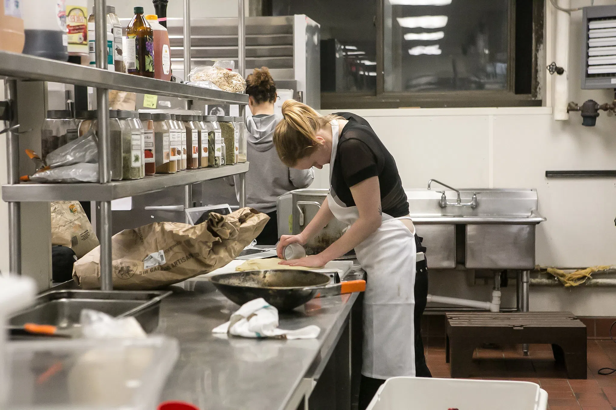 A student in an apron makes pizza dough. 