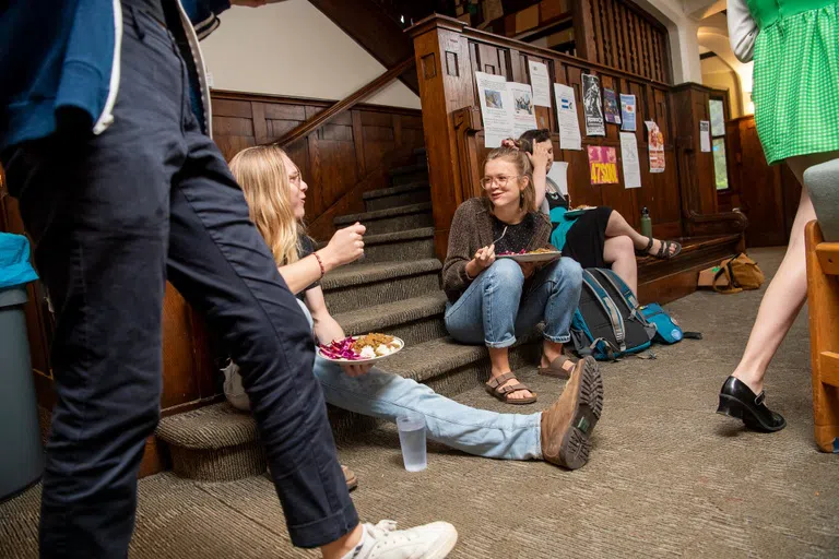 A few students sit and eat food made in OSCA - Oberlin Student Cooperative Association.