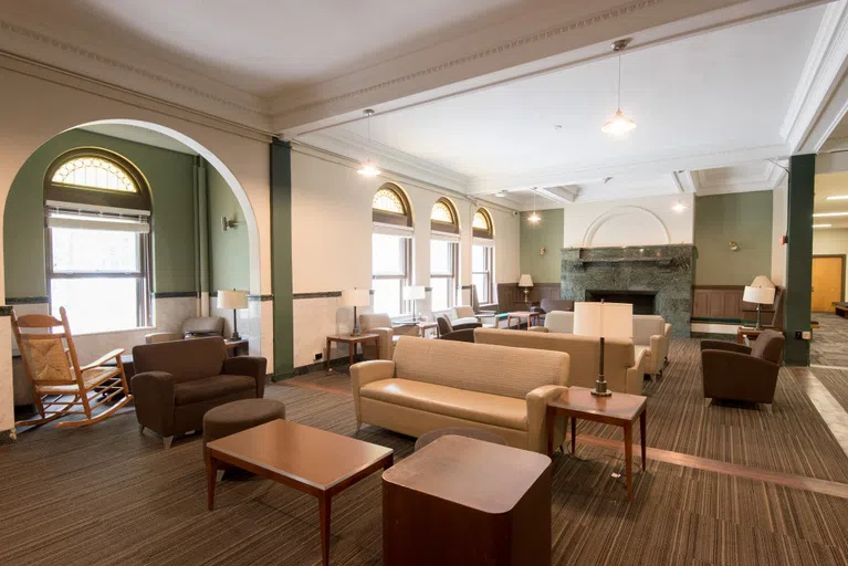 A well lit lobby of Oberlin's Student Union, Wilder, with a large fireplace and lots of tables and chairs for studying and eating. 