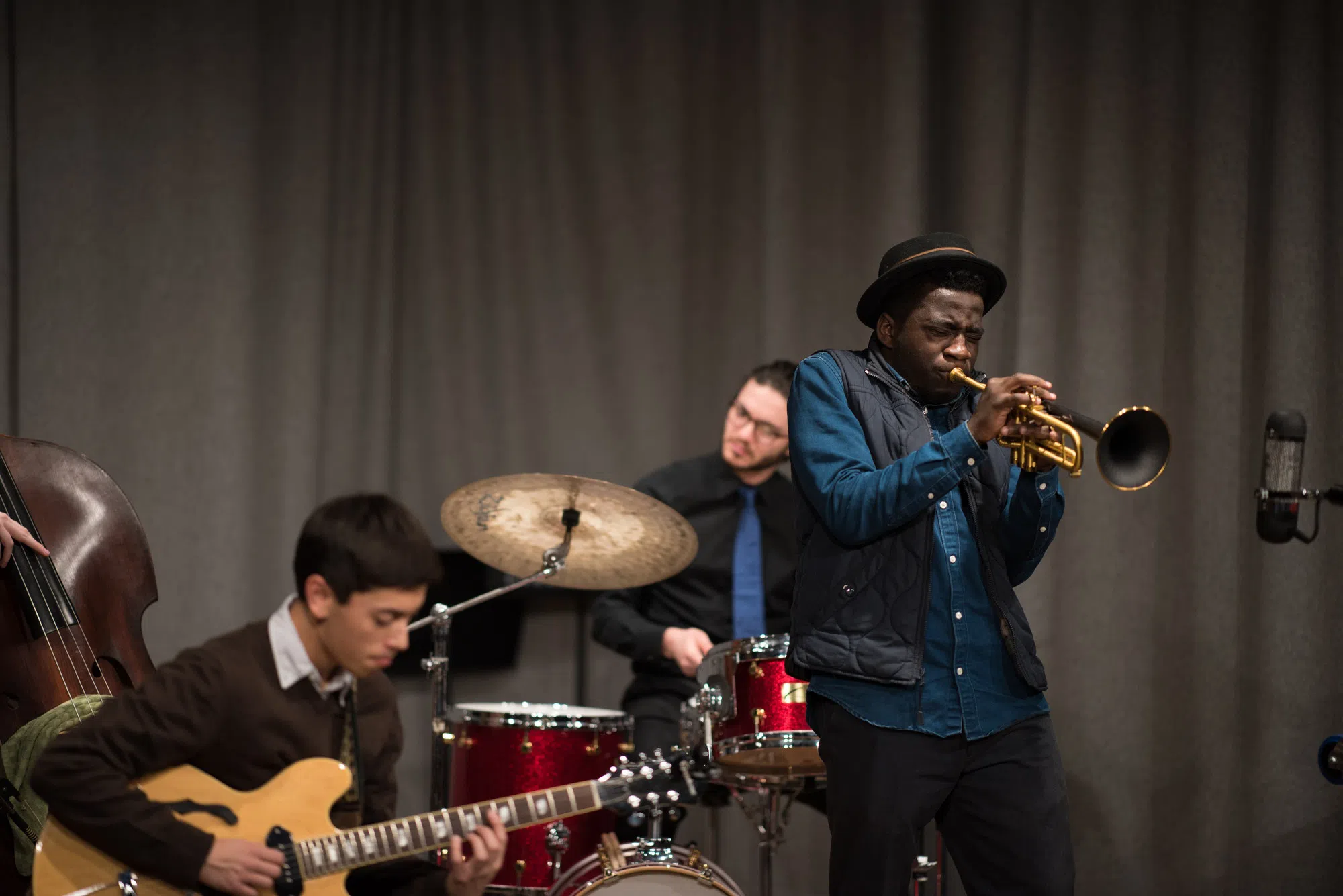 An ensemble of a trumpet player, a guitar player, and a drum player.