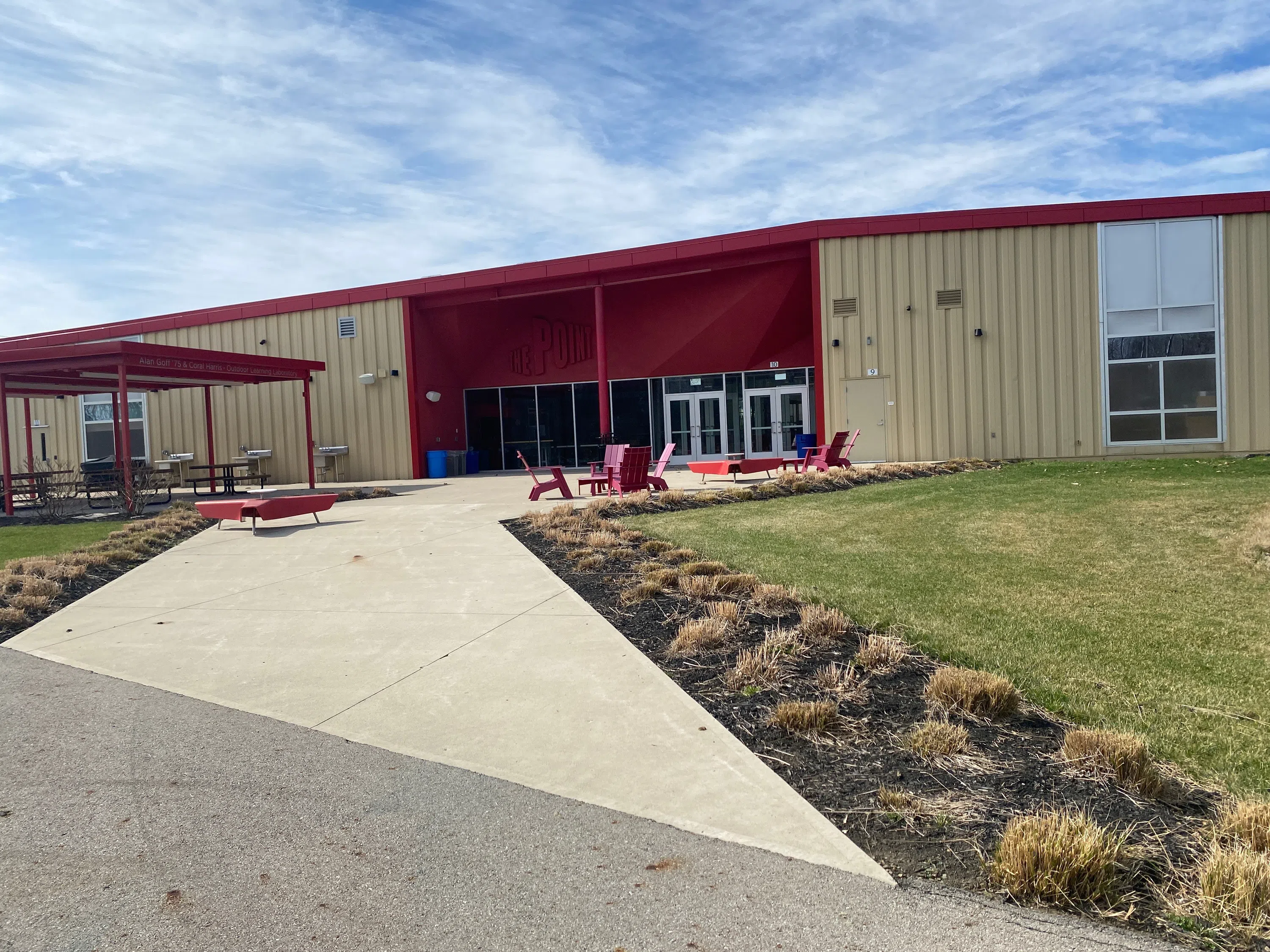 The back of The Point building. The building is red and tan with a concrete pathway leading to the doors.