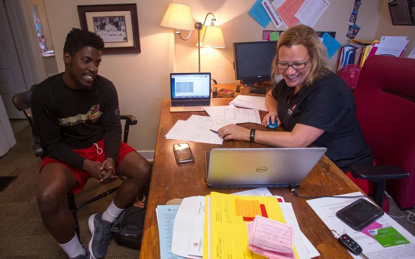 An academic adviser sits in conversation with a student in an office.