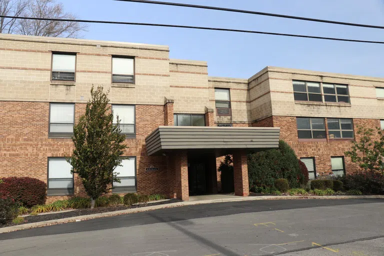 Curbside view of 25 West Home. Three story brick and concrete building with a covered entryway.