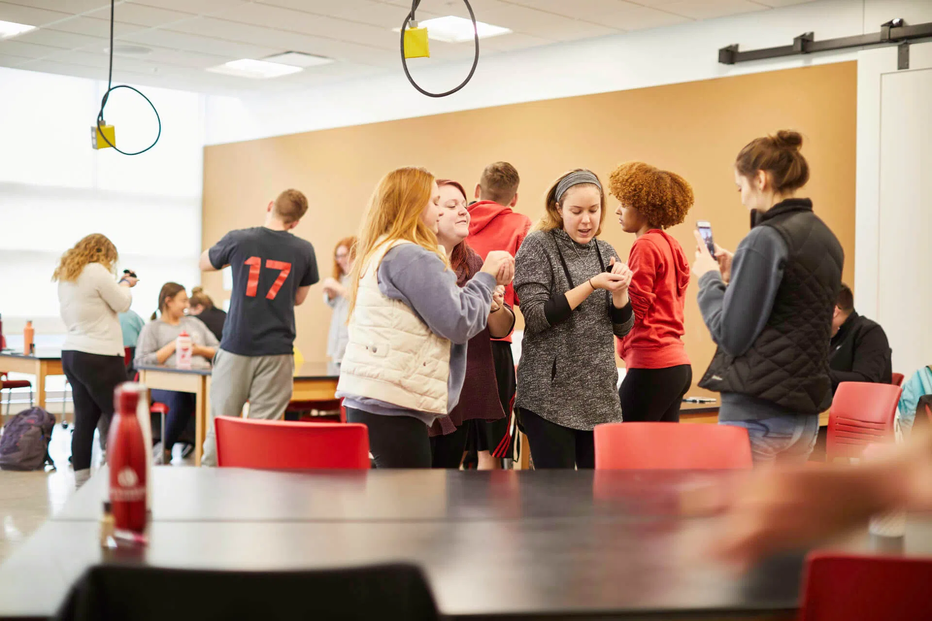 A group of people in a classroom chatting with eachother.