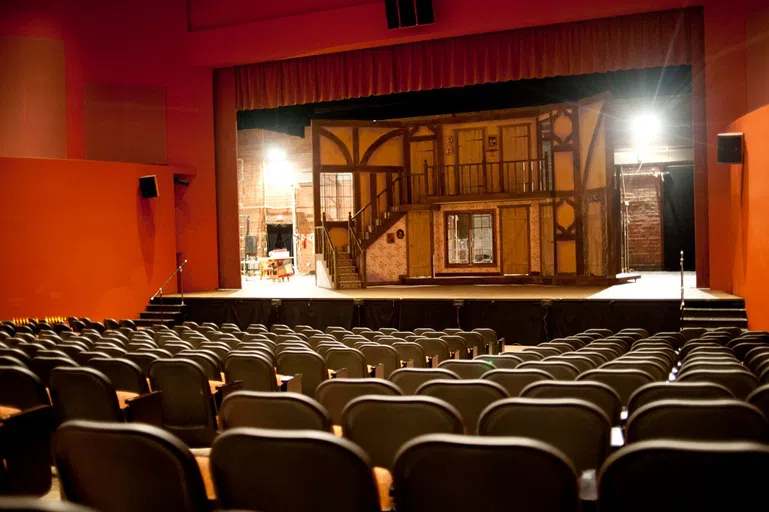 A brightly lit theater area with a wooden set on stage.