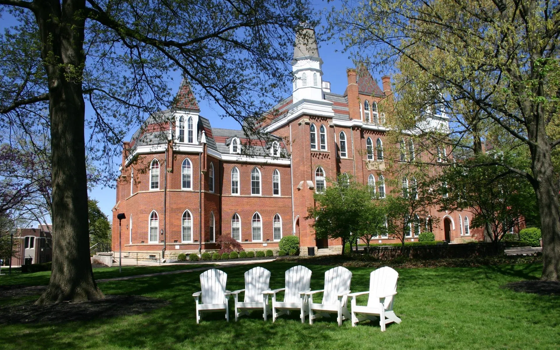 Angled view of Towers Hall and surrounding grounds showing a group of Adirondack Chairs.