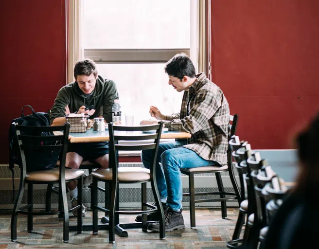 Two students sit together at a table in the Campus Center