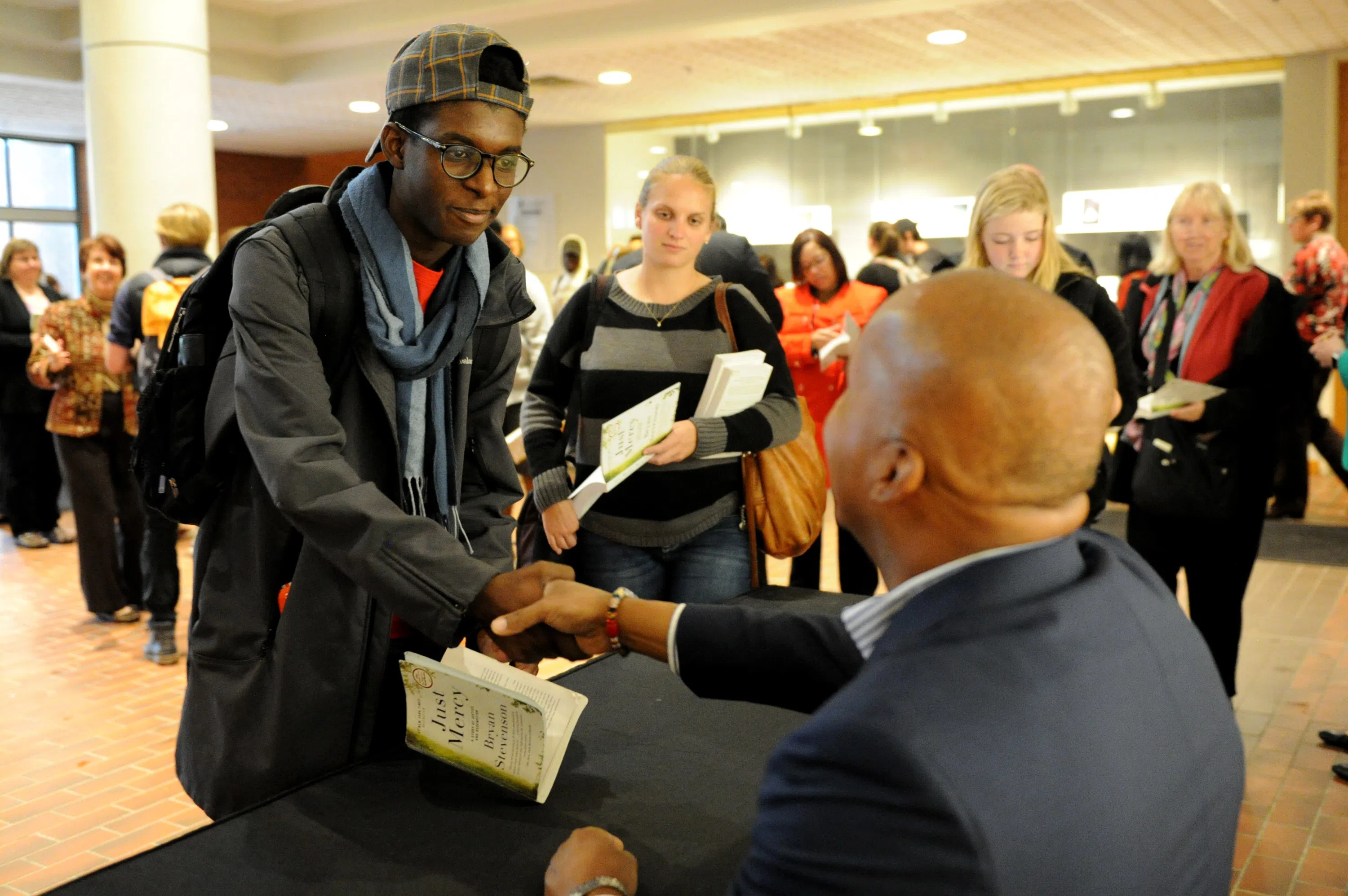 Two men shaking hands while a line forms behind them.