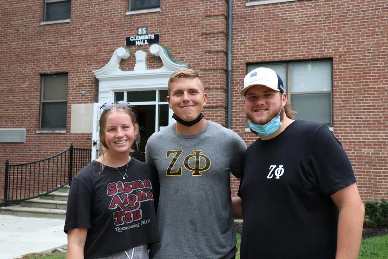 A group of students belonging to several sororities and fraternities in front of Res Hall