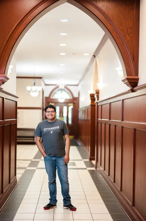 A man stands under an arched hallway in Towers