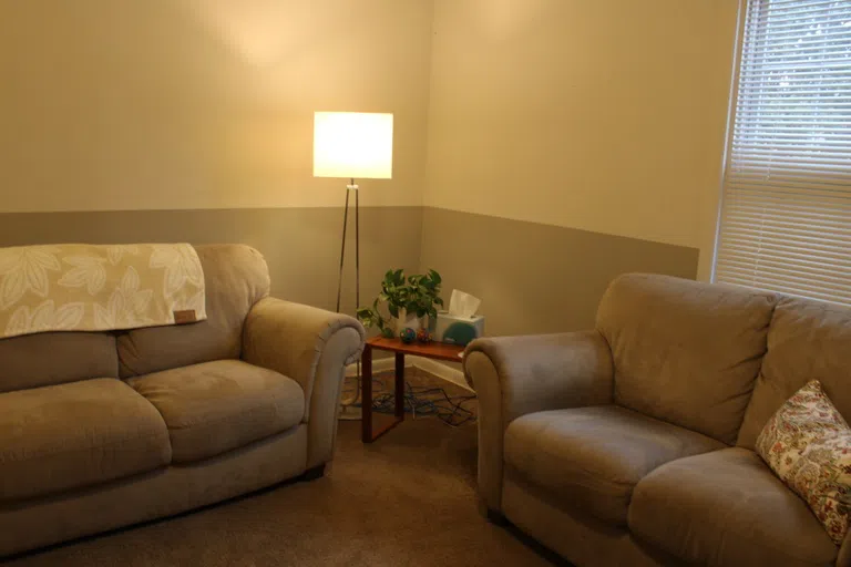 Two couches under a warm light. There is a small table with fidget toys on it.