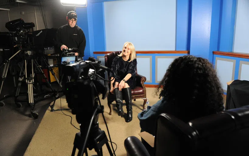 A woman smiles for a video camera in a TV Studio