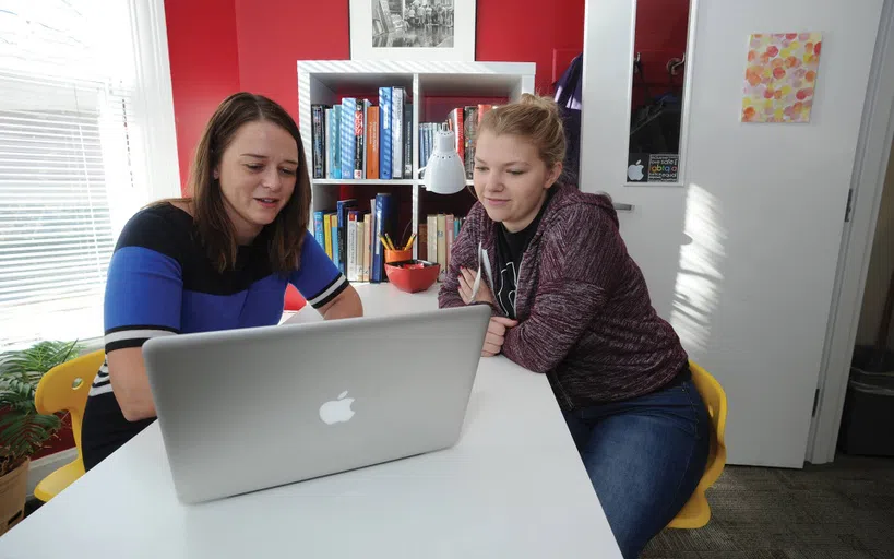 Two people looking at a MacBook together in an office