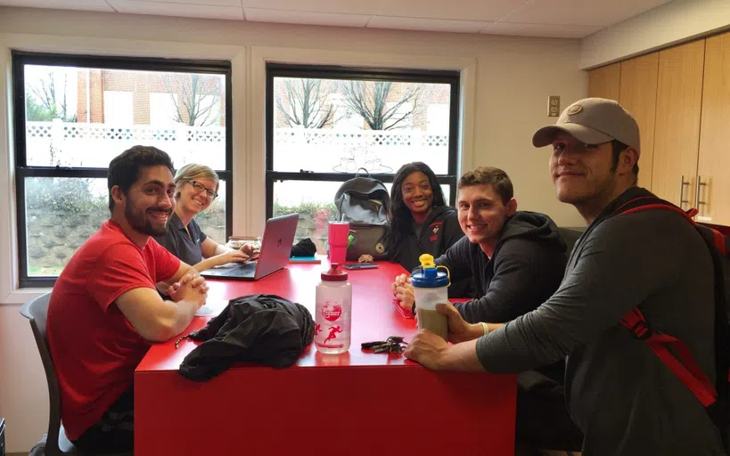 Group of people in a common space smiling for the camera.